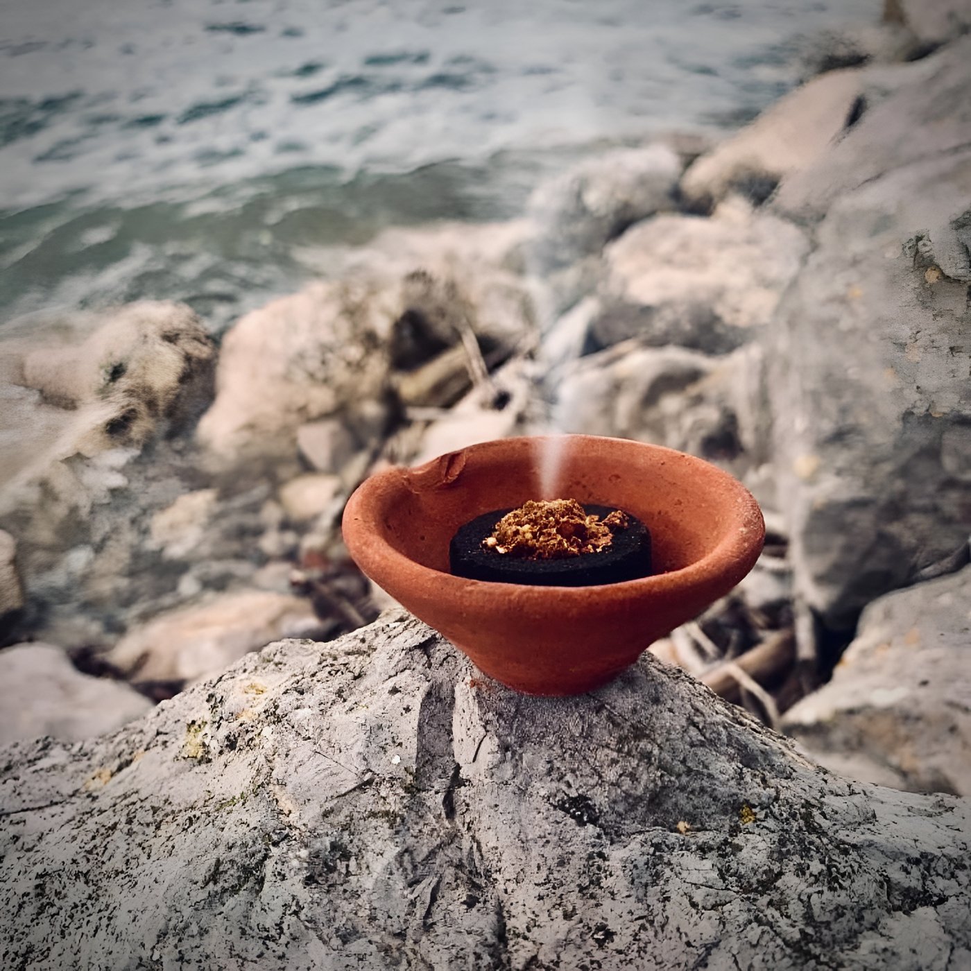 ZenFire blend burning in a clay bowl on rocks by the water